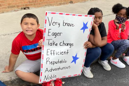An image showing Ruskin Elementary students with Veterans Day poster